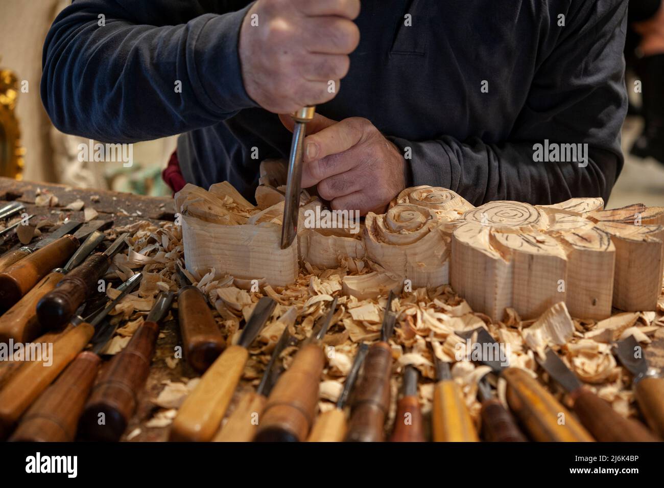 Meister des Holzschnitzers bei der Arbeit. Holzspänen, Furchen und Meißel auf der Werkbank. Stockfoto