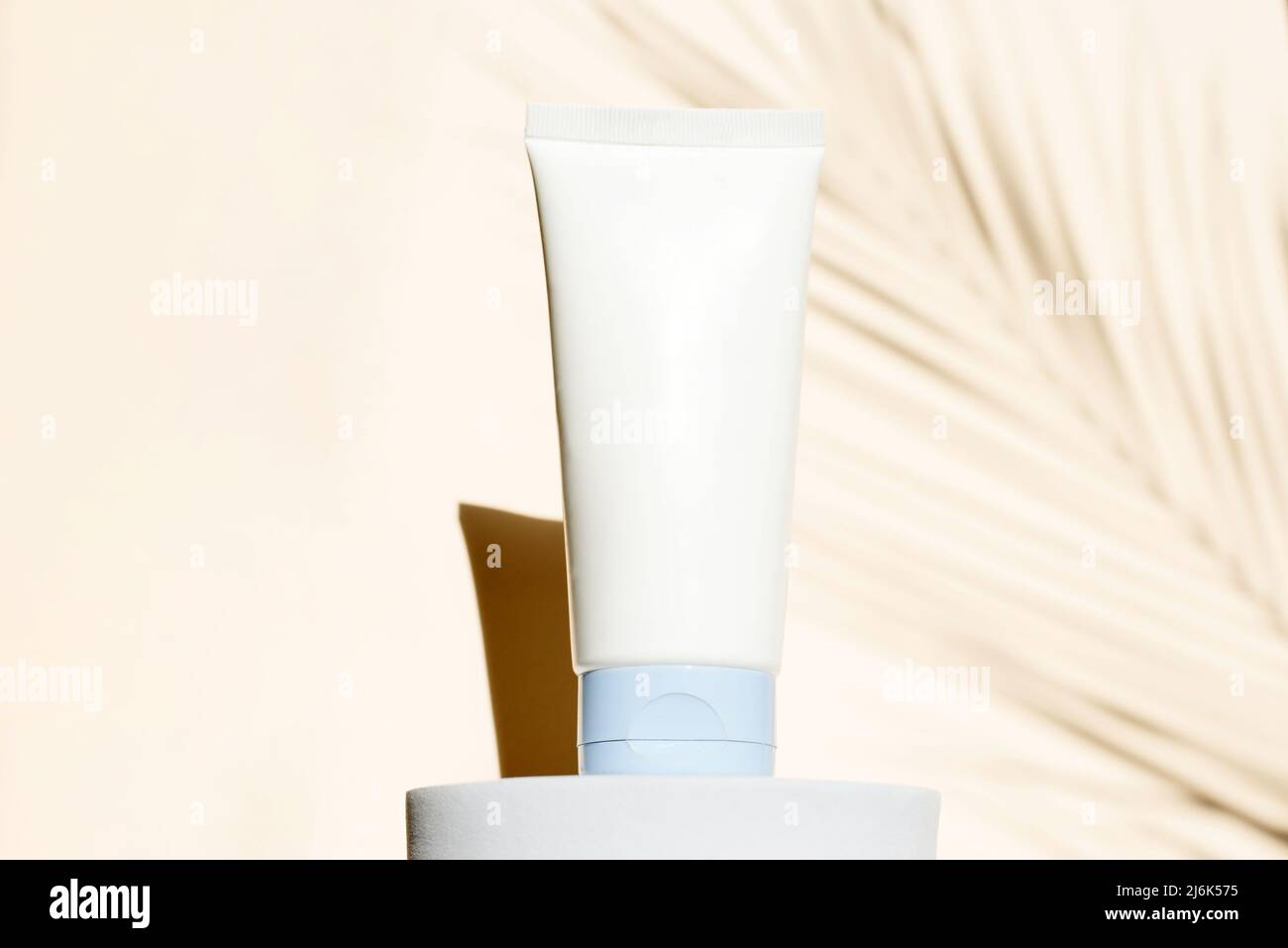 Feuchtigkeitsspendende Creme, Beauty-Produkt-Mockup in weißer Tube-Vorlage mit tropischem Blattschatten auf dem Hintergrund. Hautpflegekonzept. Stockfoto