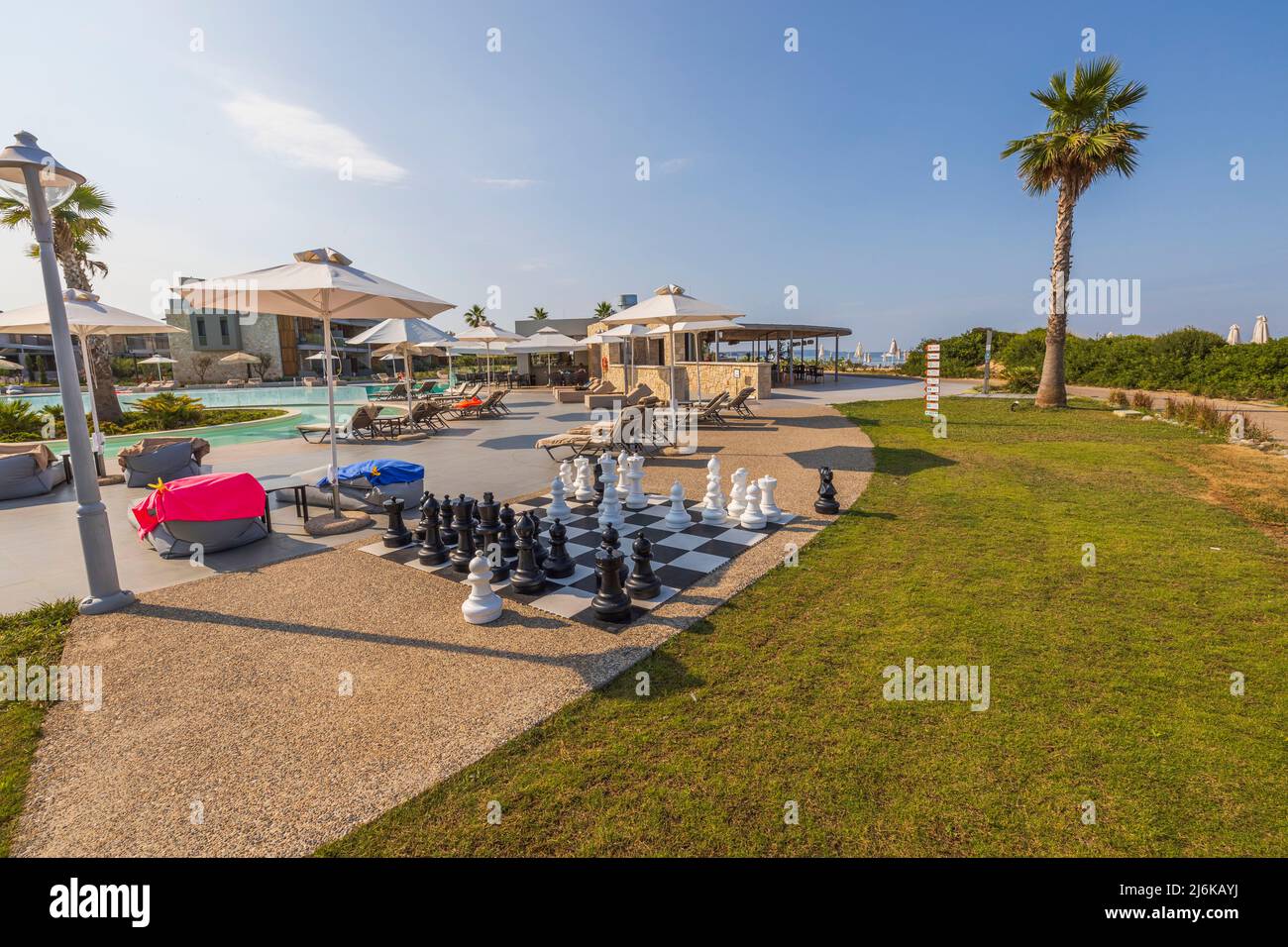 Blick auf das Hotelgelände mit großem Schachbrett und riesigen schwarz-weißen Schachfiguren für Spiele im Freien. Griechenland. Stockfoto