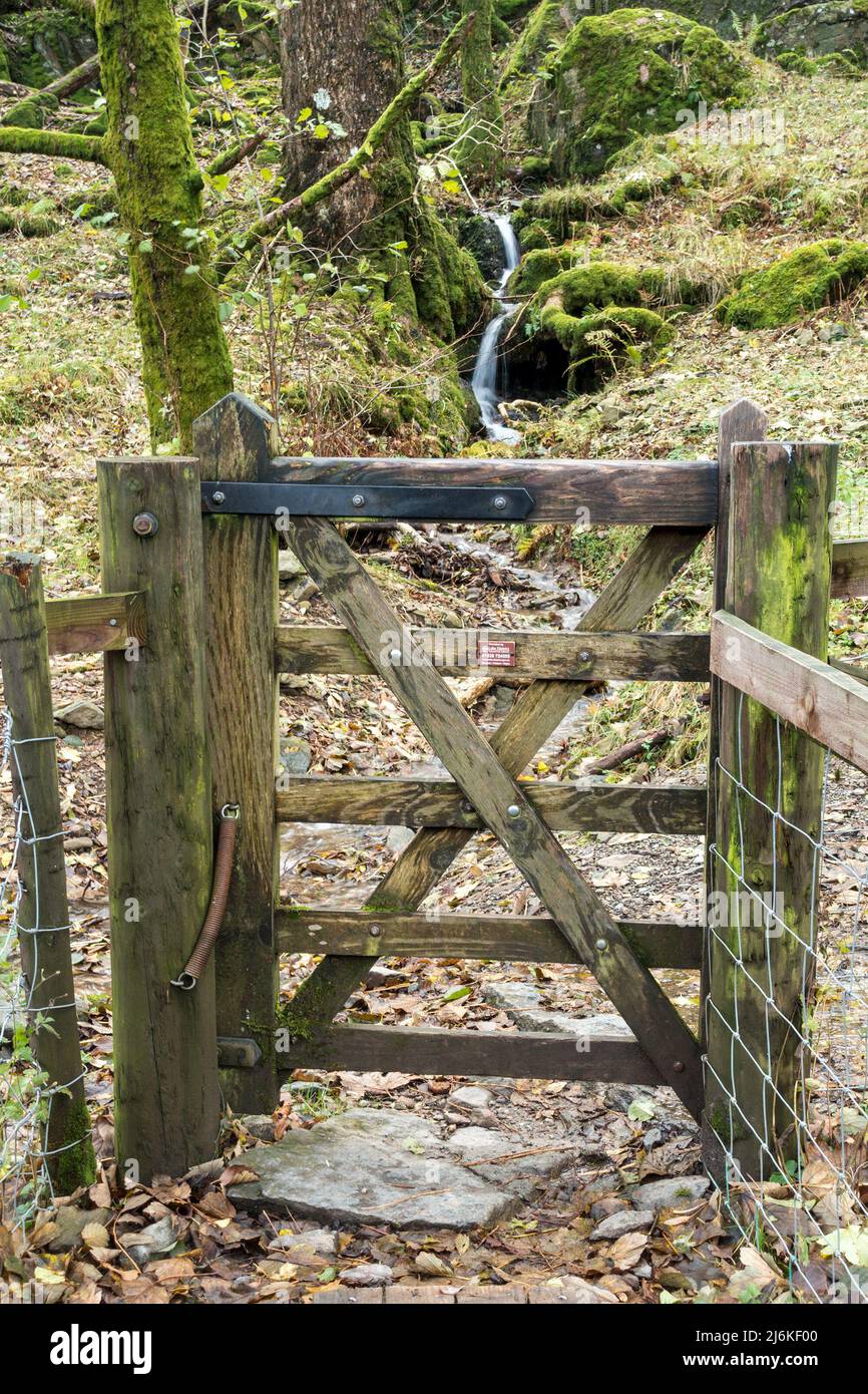 Schmale fünf Bars hölzerne Fußpfadtor mit winzigen Wasserfall dahinter, Glenridding, English Lake District, Cumbria, England, VEREINIGTES KÖNIGREICH Stockfoto