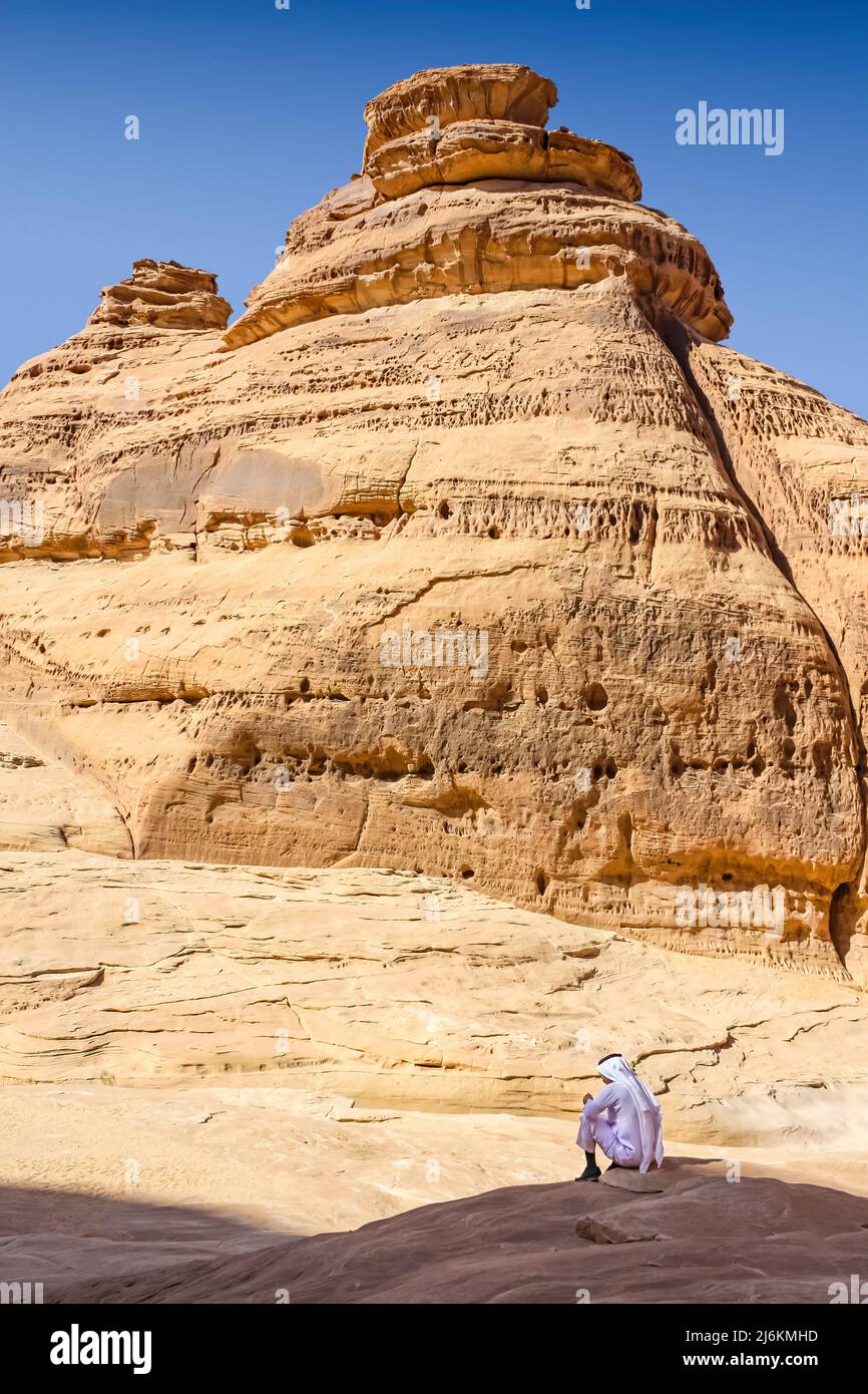 Man sitzt unter Felsformationen in Madain Saleh, Hegra, Saudi-Arabien Stockfoto