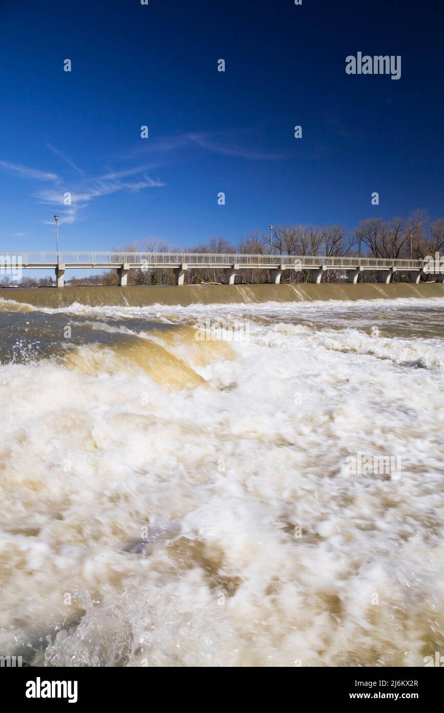 Fußgängerbrücke und Wasserflusskontrolldamm über dem Fluss Mille-Iles mit einem hohen Wasserstand im Frühjahr, Terrebonne, Lanaudiere, Quebec, Kanada Stockfoto