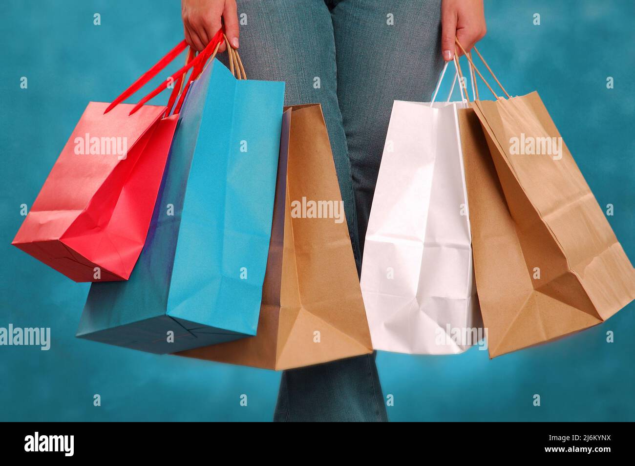 Die Hände einer Frau, die mehrere Einkaufstaschen aus Papier hält Stockfoto