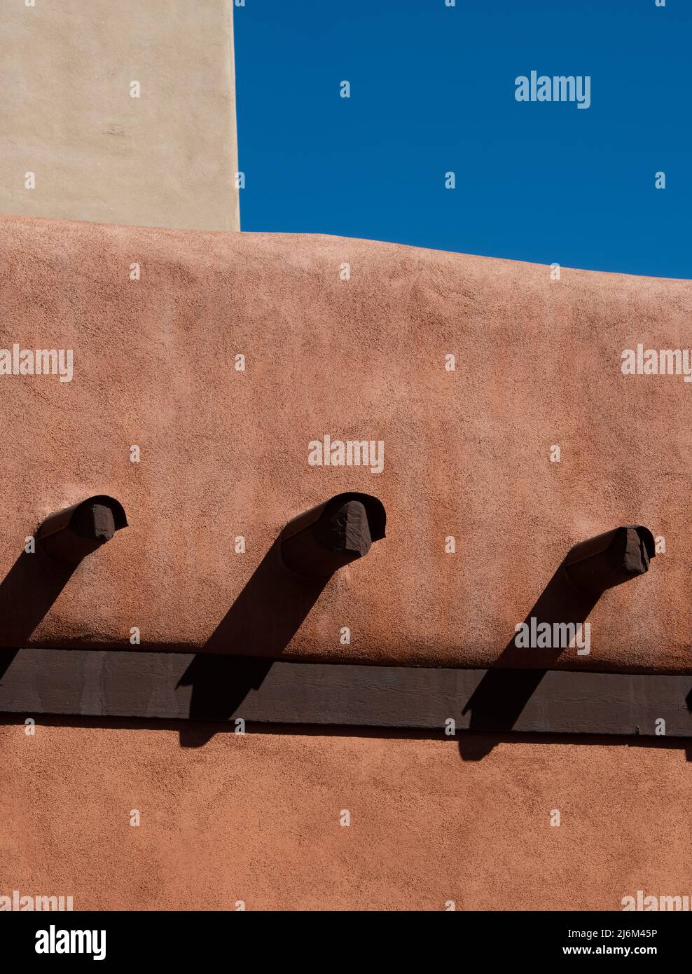 Große Holzbalken ragen von der Betonaußenwand des adobe-Hauses oder -Hauses in Santa Fe, New Mexico, USA Stockfoto