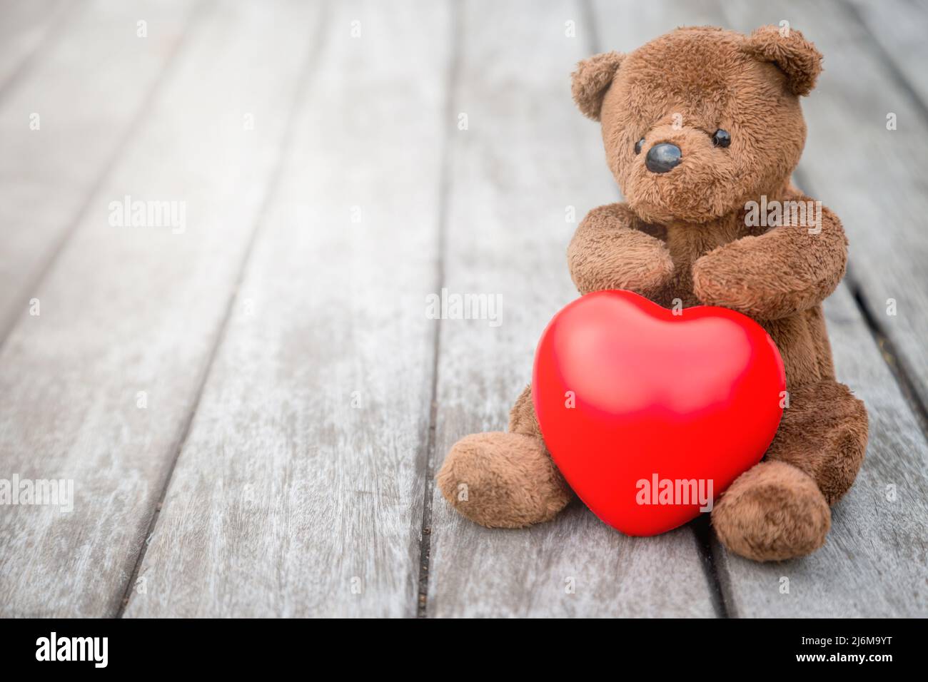 Brauner Bär und Rotes Herz mit altem Holzhintergrund für die Pflege Ihrer Liebe Stockfoto