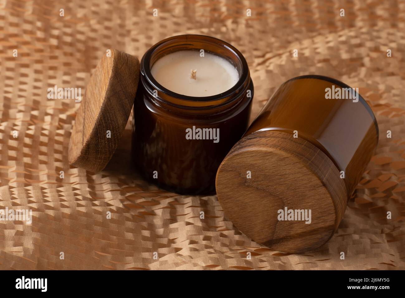 Sojalkerzen in einem braunen Glasgefäß mit einem Holzdeckel. Aromatherapie. Kerze auf beigem Hintergrund Nahaufnahme. Für ein Etikett platzieren. Wachs und Docht. Inneneinrichtung. Handgefertigt. Lufterfrischer. Sojakerze-Konzept Stockfoto