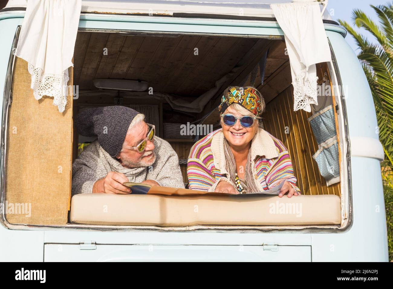 Glückliches Rentnerpaar im Retro-Vintage-Stil van oder Camper Planung einer Reise auf der Karte. Altes Paar genießt Urlaub Reisen im Wohnmobil. Stockfoto