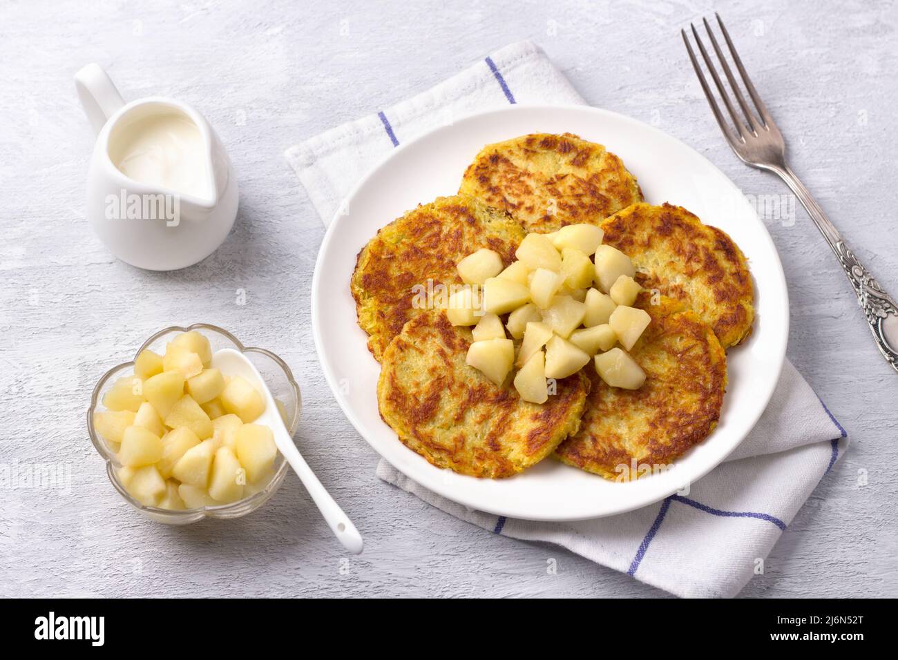 Traditionelle Latkes-Krapfen mit saurer Creme- und Apfelsauce auf hellgrauem texturiertem Hintergrund, Draufsicht Stockfoto