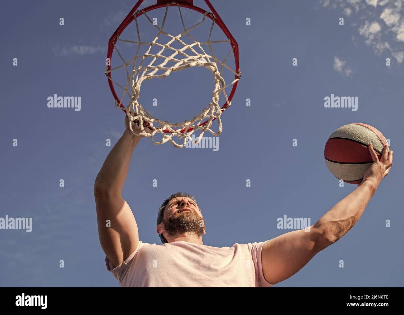 Sommeraktivität. Starker Mann mit Basketballball auf dem Platz. Professioneller Basketballspieler Stockfoto