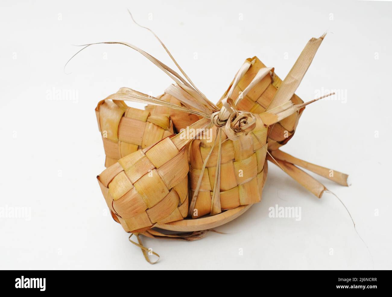 Ketupat Reisdumpling Spezialgericht serviert im Eid Mubarak. Ketupat isoliert auf weißem Hintergrund. Ketupat ist gekochter Reis mit jungen Kokosnussblättern Casin Stockfoto