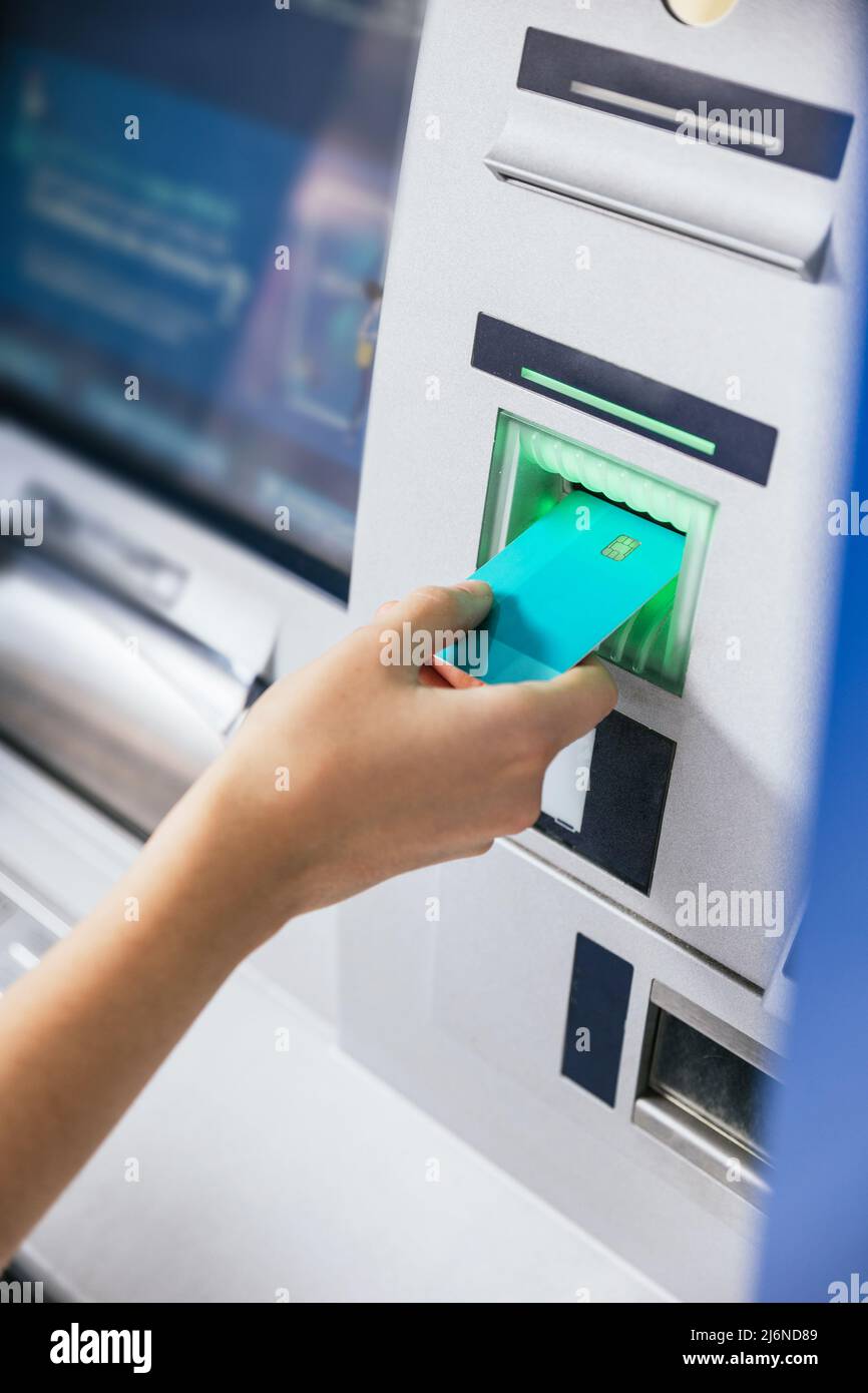 Nahaufnahme der Hand einer jungen Frau, die eine Kreditkarte in einen Geldautomaten einführt, um Geld zu überweisen oder abzuheben. Finanzkunden- und Bankservice Stockfoto