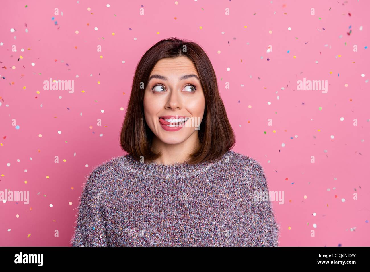 Portrait von attraktiven braunhaarigen funky fröhlich Mädchen fliegen Konfetti Lippe auf rosa Pastellfarben Hintergrund isoliert lecken Stockfoto