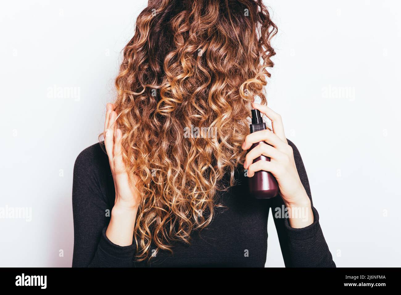 Junge Frau mit dicken lockigen Haaren Anwendung Haarpflege-Serum Stockfoto