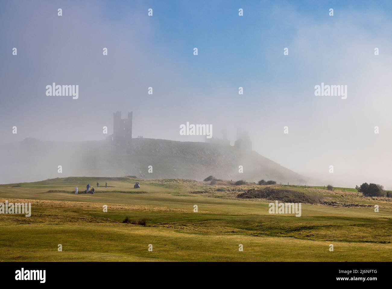 Auf der anderen Seite des Golfplatzes mit Dunstanburgh Castle im Meeresnebel, Northumberland Coast Path, England Stockfoto