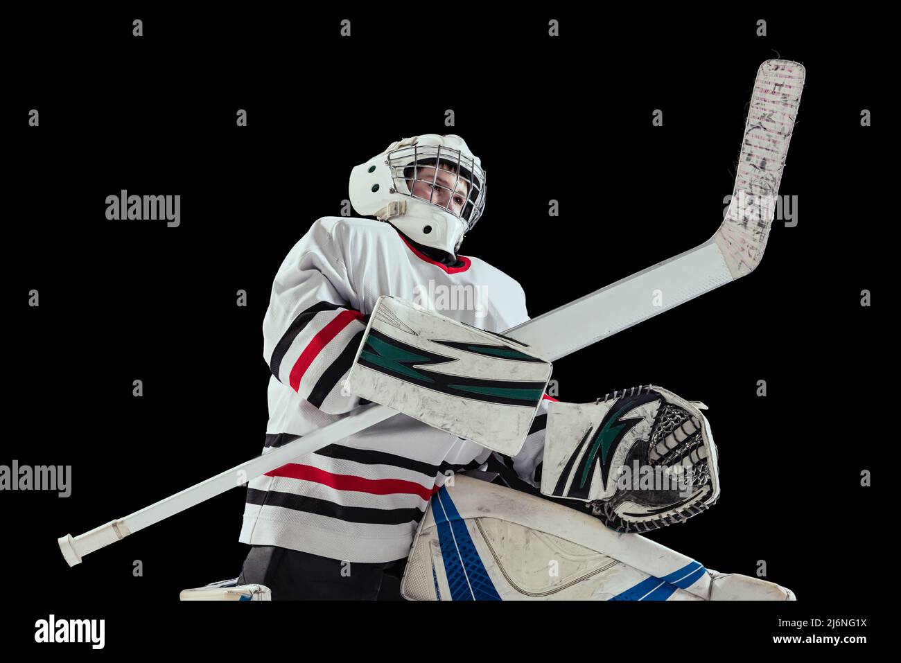 Porträt eines Teenagers, Eishockeyspielers, Torwarts, der isoliert auf schwarzem Studiohintergrund trainiert. Dynamischer Sport Stockfoto