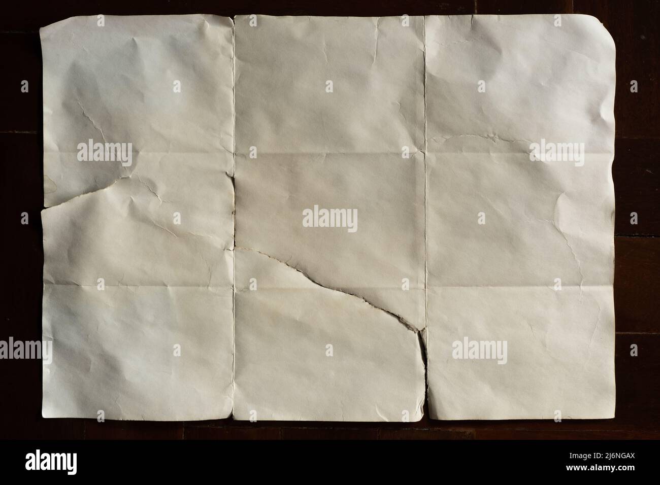 Altes, weißes gefaltetes Papier auf dunklem Holzhintergrund Stockfoto