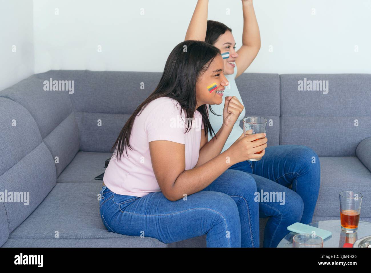 Lateinamerikanische Freundinnen, die sich zu Hause ein Fußballspiel ansehen Stockfoto