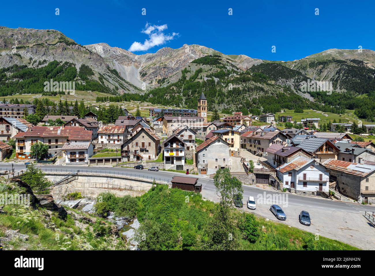 Blick von oben auf die kleine alpine Stadt Bersezio am Fuße der Berge unter blauem Himmel im Piemont, Norditalien. Stockfoto