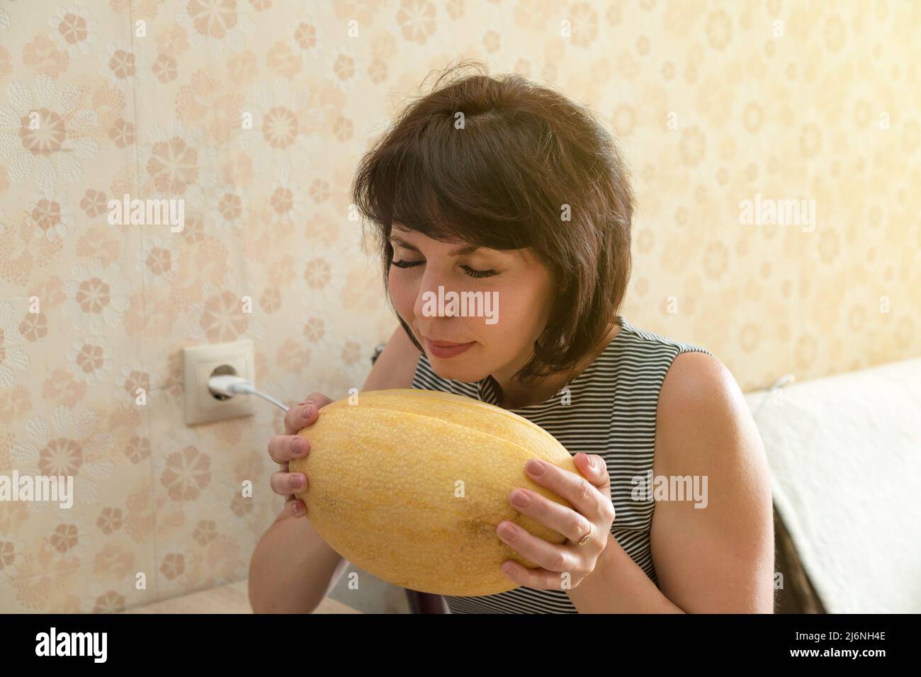 Eine Erwachsene Brünette Frau hält große gelbe Melone inhalieren angenehmen Duft. Stockfoto