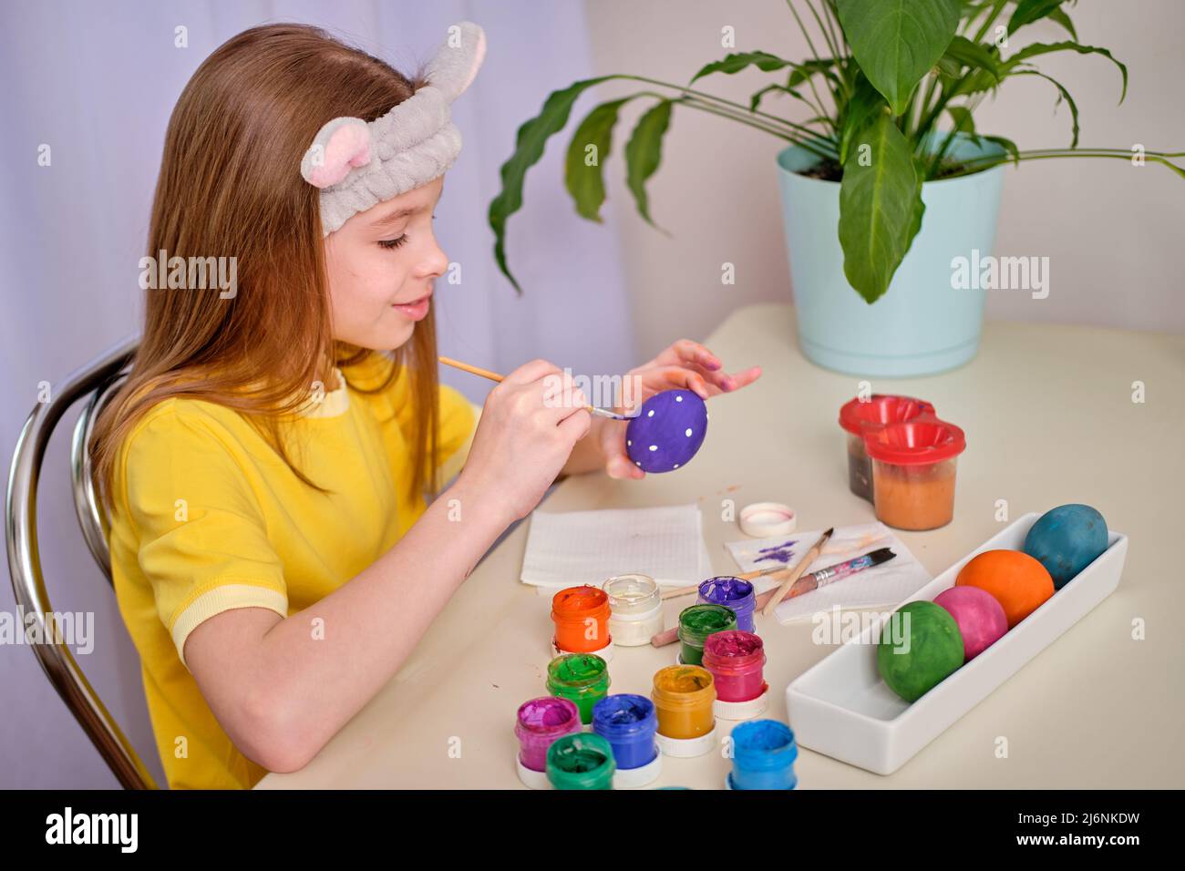 Ein Kind malt Ostereier mit Farben. Porträt des kaukasischen Mädchen, Kind 9-10 Jahre alt Dekoration ostereier in der heimischen Küche. Das Konzept o Stockfoto