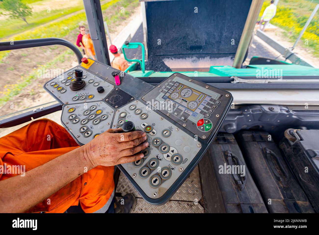 Arbeiter, Fahrer steuert Asphalt Straße Verlegemaschine mit Lenker, Joystick zu bedienen. Stockfoto