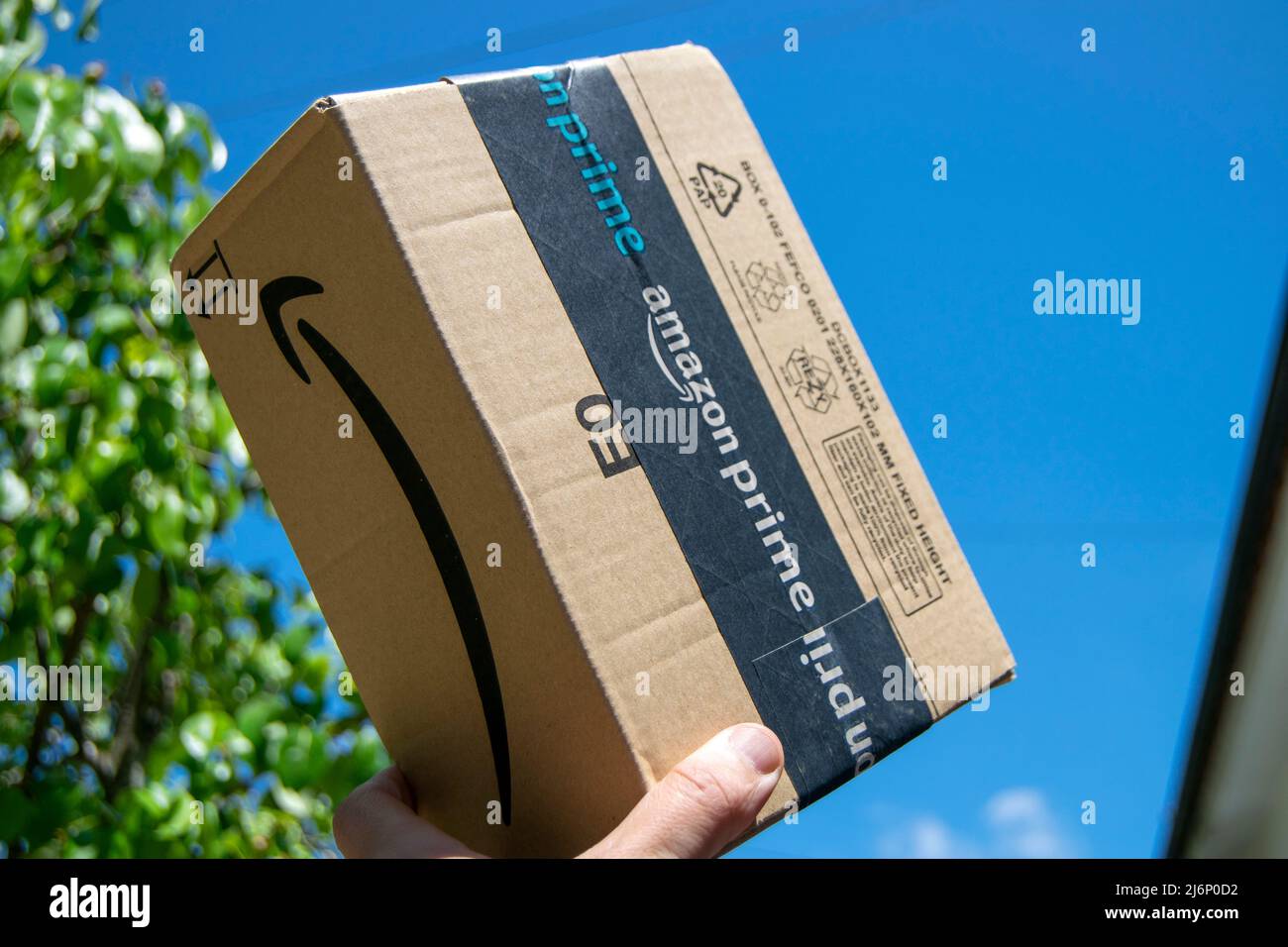 Amazon Prime schneller und erstklassiger Lieferservice. Amazon prime-Paket, Online-E-Commerce schnell und sicher. Lieferung Junge mit Amazon-Paket. Stockfoto