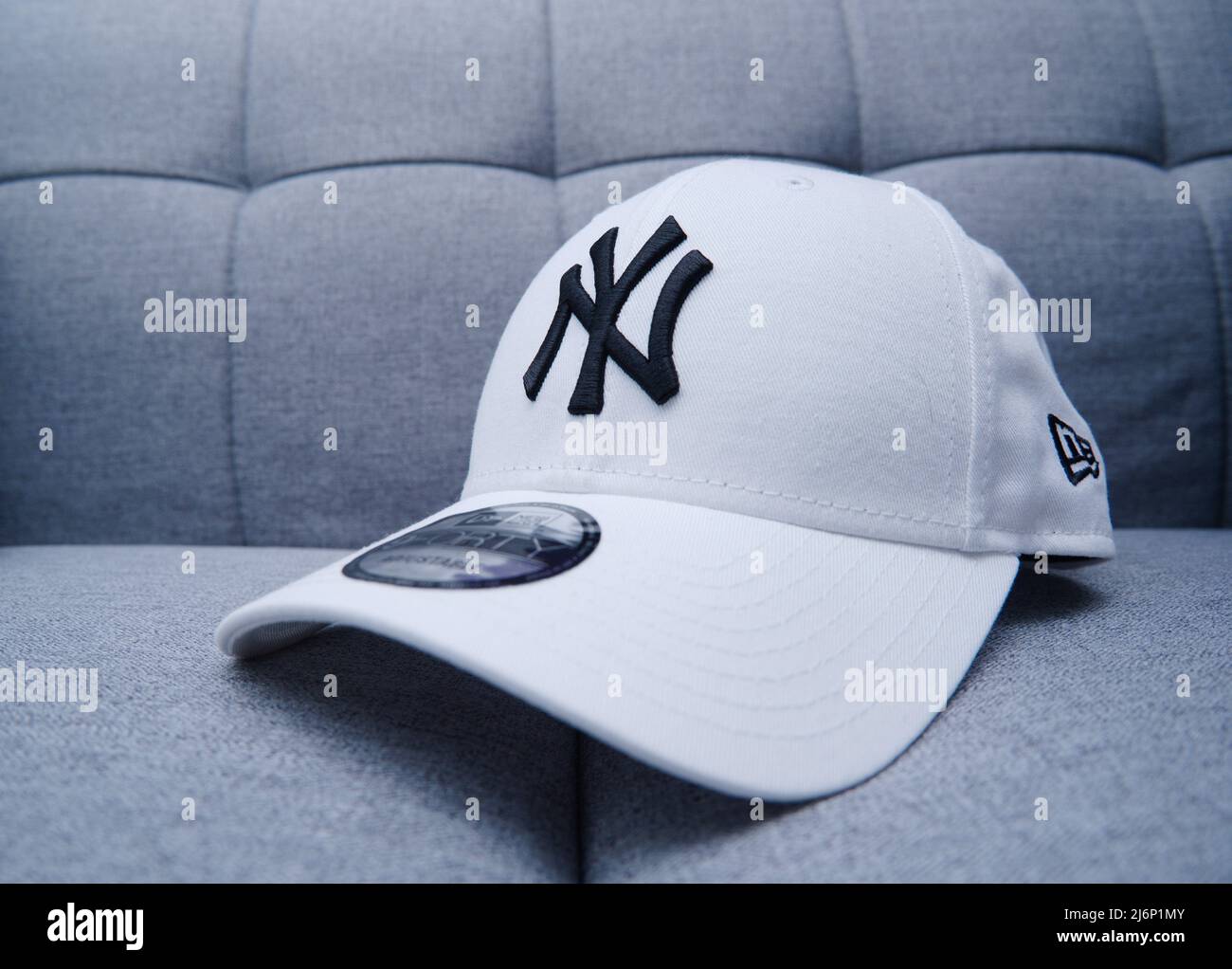 Hongkong - 3. Mai 2022: Weiße New York Yankees Snapback-taillierte Baseballmütze für Männer auf grauer Couch. Mit Chunky Embroidery und Sticker. Stockfoto