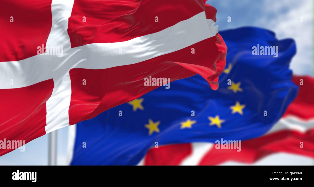 Detail der im Wind winkenden Nationalflagge Dänemarks mit verschwommener eu-Flagge im Hintergrund an einem klaren Tag. Demokratie und Politik. E Stockfoto