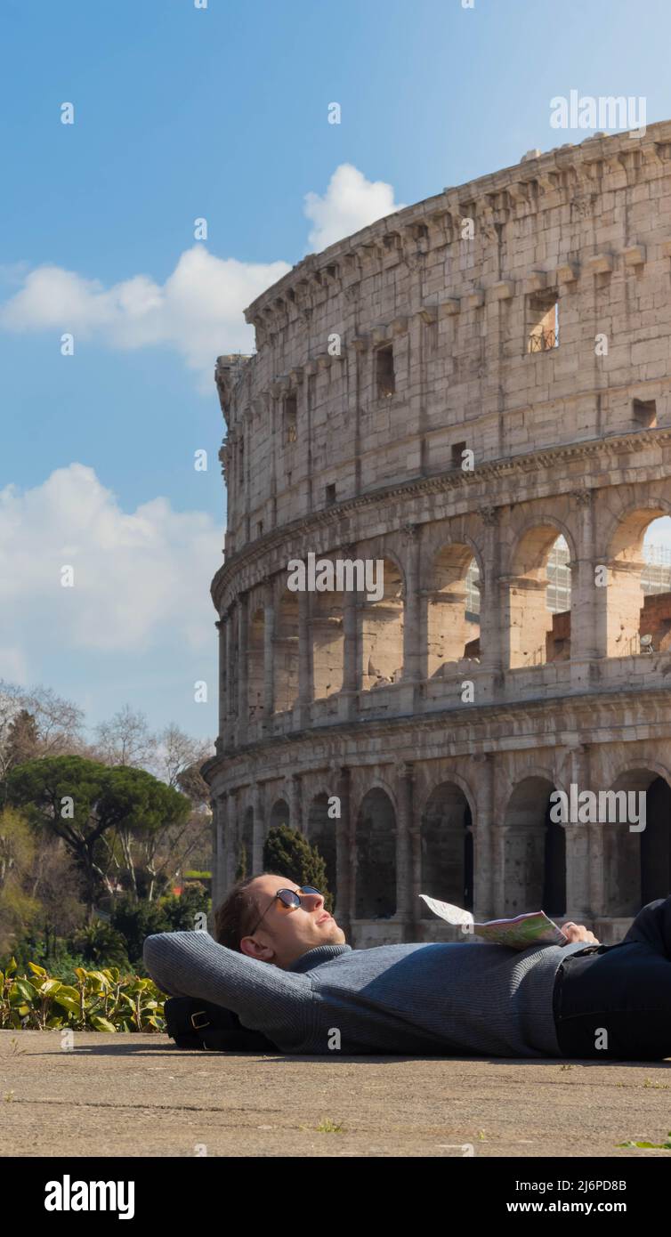 Junger Mann im Urlaub in Rom beim Sonnenbaden vor dem römischen Kolosseum in Italien Stockfoto