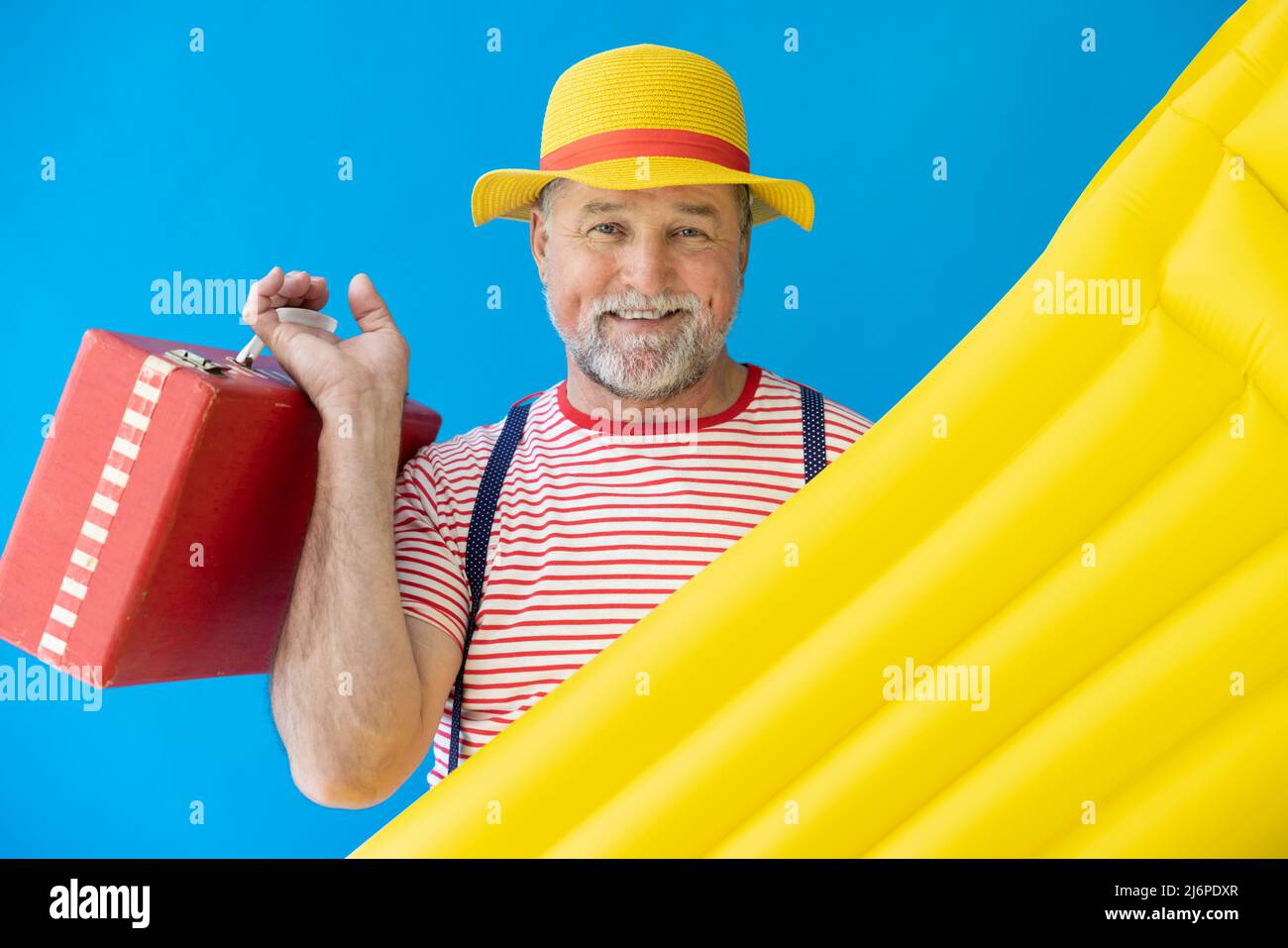 Glücklicher älterer Mann, bereit zu reisen. Person mit gelber Luftmatratze. Sommerurlaub und Urlaubskonzept Stockfoto