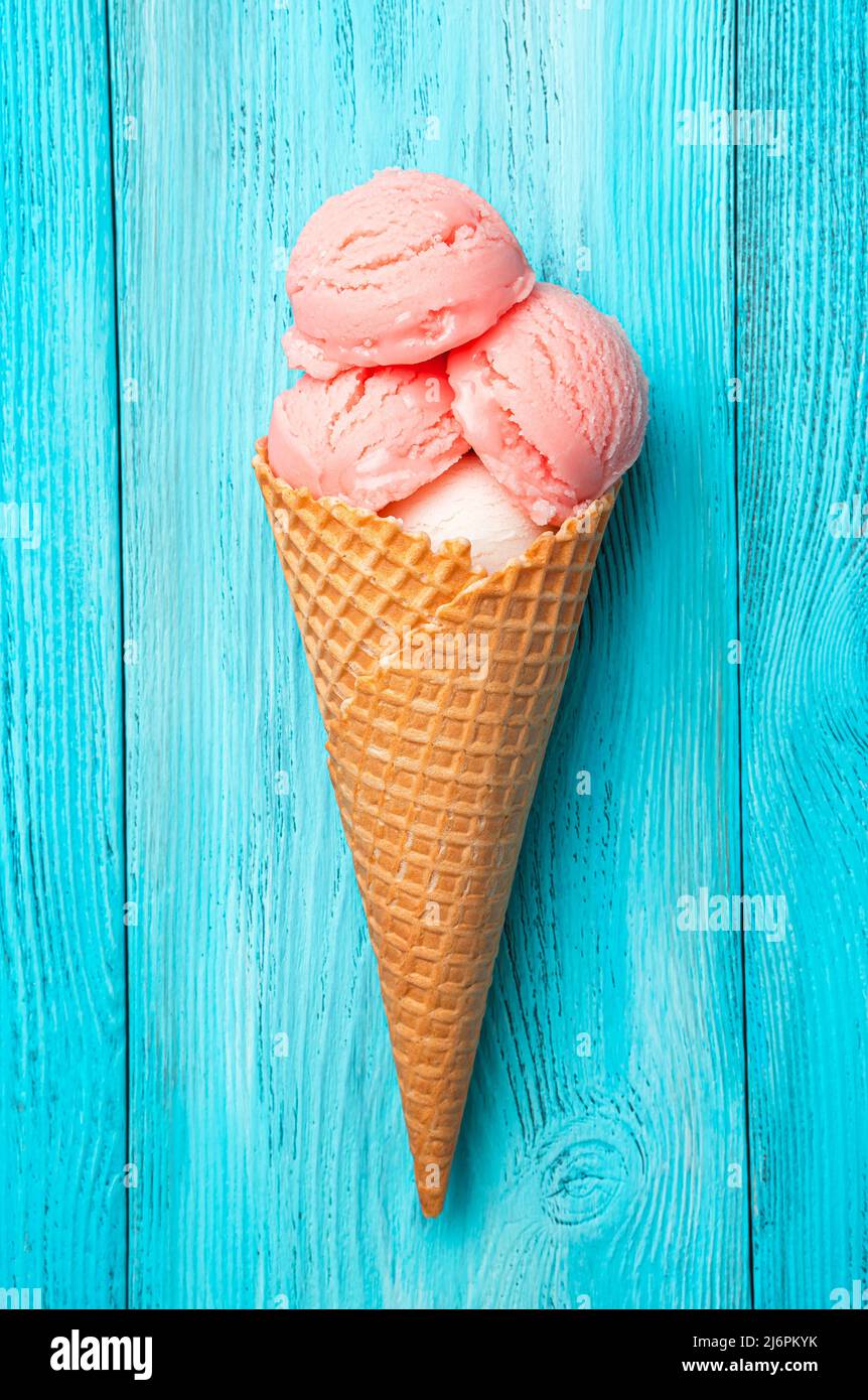 Himbeer-Eis in einem Waffelkegel auf blauem Hintergrund. Stockfoto