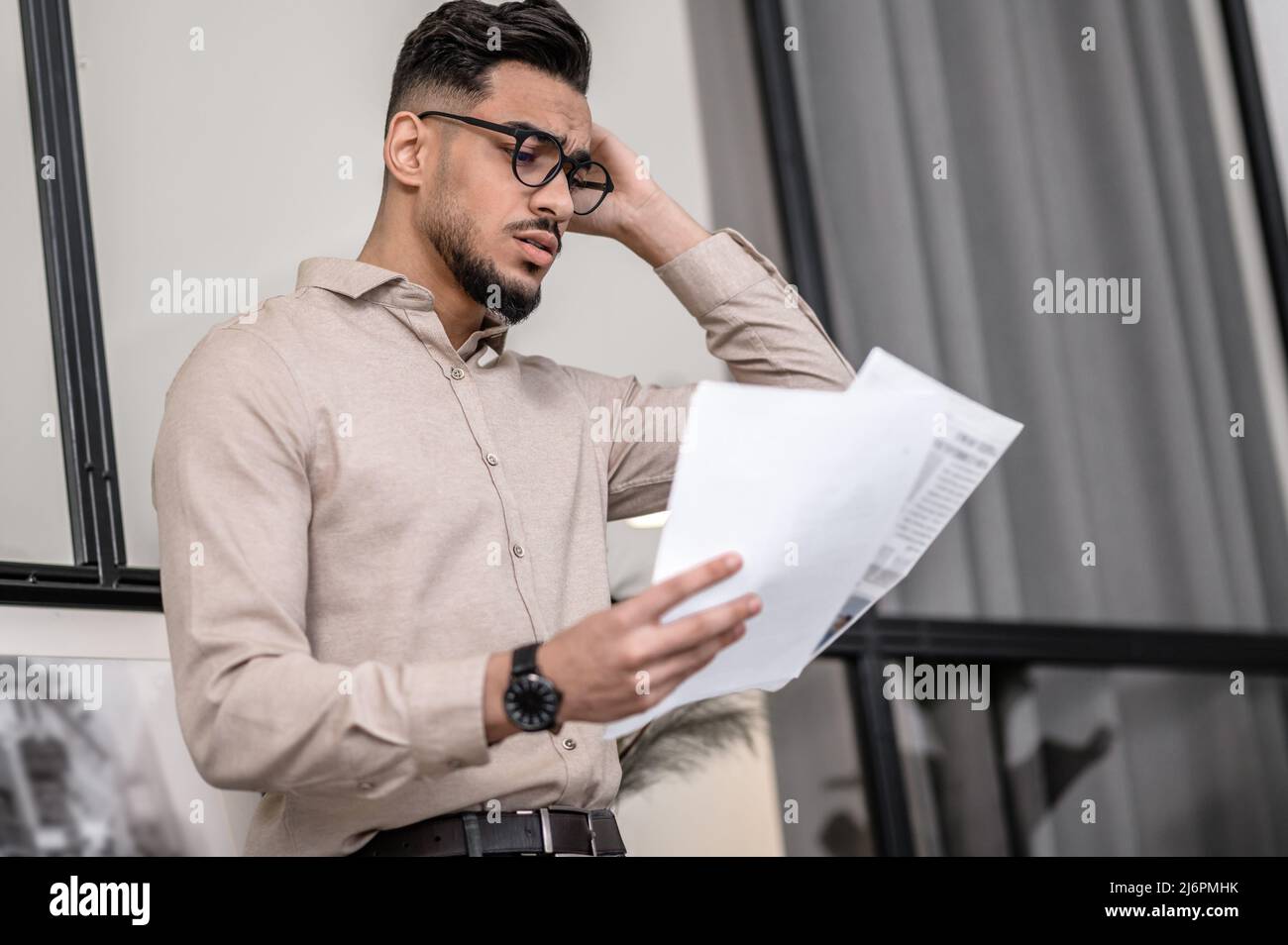 Ein junger Mann, der beim Lesen eines Papiers nachdenklich aussieht Stockfoto