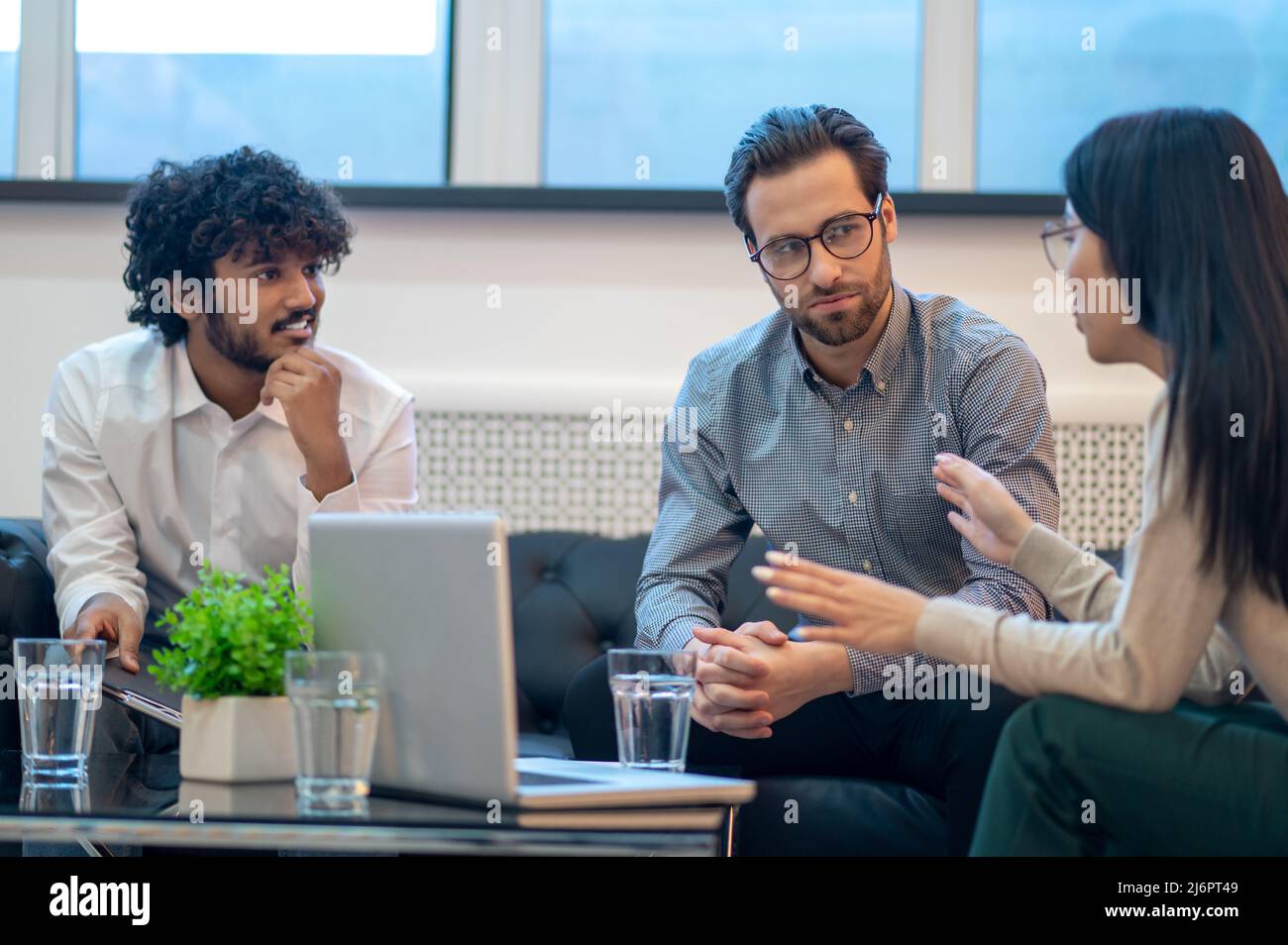 Drei Mitarbeiter des Unternehmens halten eine Gruppendiskussion ab Stockfoto