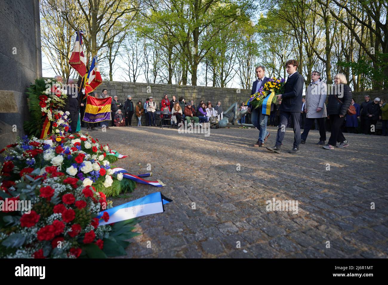 03. Mai 2022, Hamburg: Eine Delegation des Generalkonsulats der Ukraine trägt anlässlich des 77.. Jahrestages des Kriegsendes und der Befreiung der Gefangenen in der KZ-Gedenkstätte Neuengamme einen Blumenkranz zur Gedenkstätte. Überlebende sowie Mitgliedsorganisationen der Amicale Internationale KZ Neuengamme und andere Verwandte ehemaliger KZ-Häftlinge aus Belgien, Dänemark, Deutschland, Frankreich, Kroatien, Die Niederlande, Polen, Spanien und die Ukraine nahmen an dem Gedenken Teil. Foto: Marcus Brandt/dpa Stockfoto