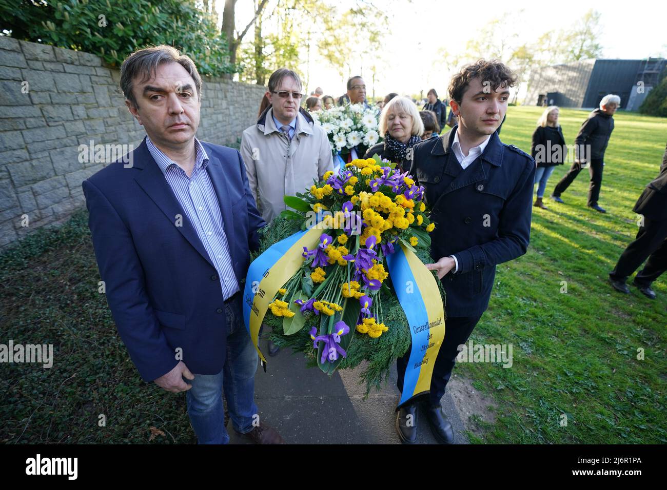 03. Mai 2022, Hamburg: Eine Delegation des Generalkonsulats der Ukraine trägt anlässlich des 77.. Jahrestages des Kriegsendes und der Befreiung der Gefangenen in der KZ-Gedenkstätte Neuengamme einen Blumenkranz zur Gedenkstätte. Überlebende sowie Mitgliedsorganisationen der Amicale Internationale KZ Neuengamme und andere Verwandte ehemaliger KZ-Häftlinge aus Belgien, Dänemark, Deutschland, Frankreich, Kroatien, Die Niederlande, Polen, Spanien und die Ukraine nahmen an dem Gedenken Teil. Foto: Marcus Brandt/dpa Stockfoto