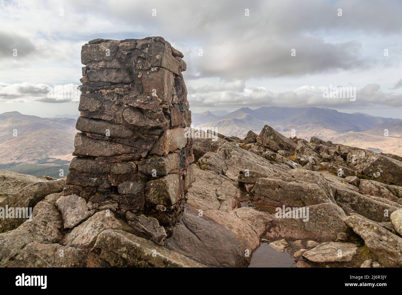 Der Trig Point auf dem Gipfel des Moel Siabod, mit Blick auf einen wolkenbedeckten Snowdon im Hintergrund Stockfoto