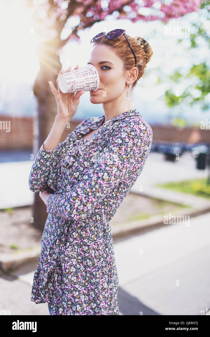 Junge Rotschopf Frau trinken aus Kunststoff-Kaffeetasse im Frühling Stockfoto