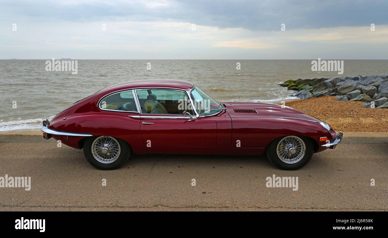 Classic Red E Typ Jaguar geparkt an Strandpromenade Strand und Meer im Hintergrund Stockfoto