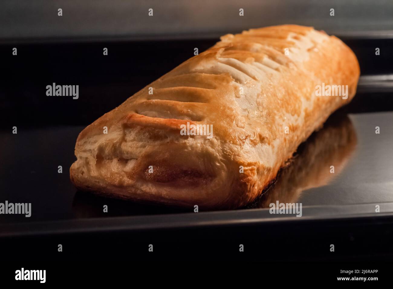 Ein gebackenes hausgemachtes Brötchen mit Apfelmarmelade im Elektroofen: Nahaufnahme Stockfoto