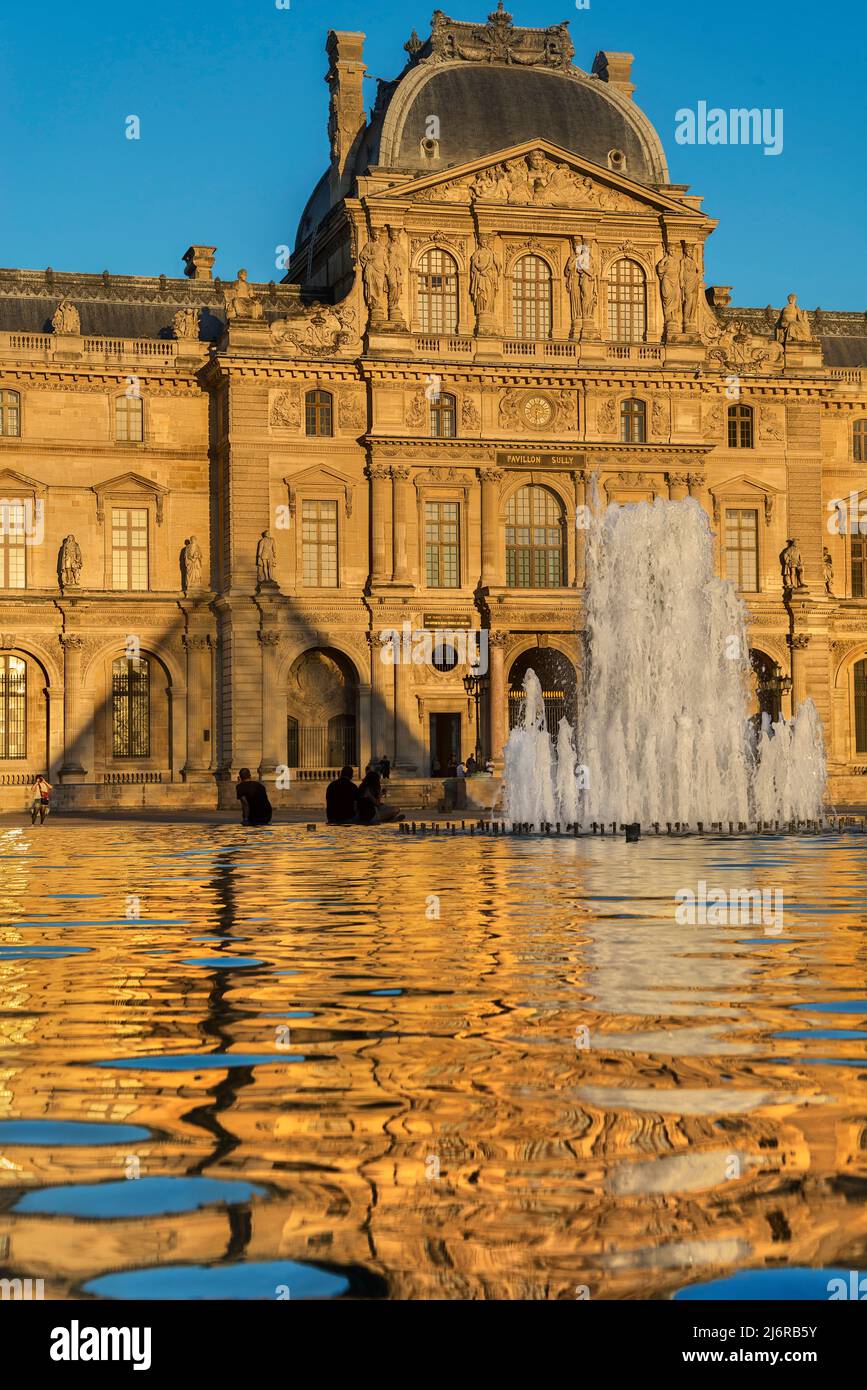 Der Pavillon de Sully des musée du Louvre spiegelt sich bei Sonnenuntergang in einem Wasserbecken wider. Stockfoto