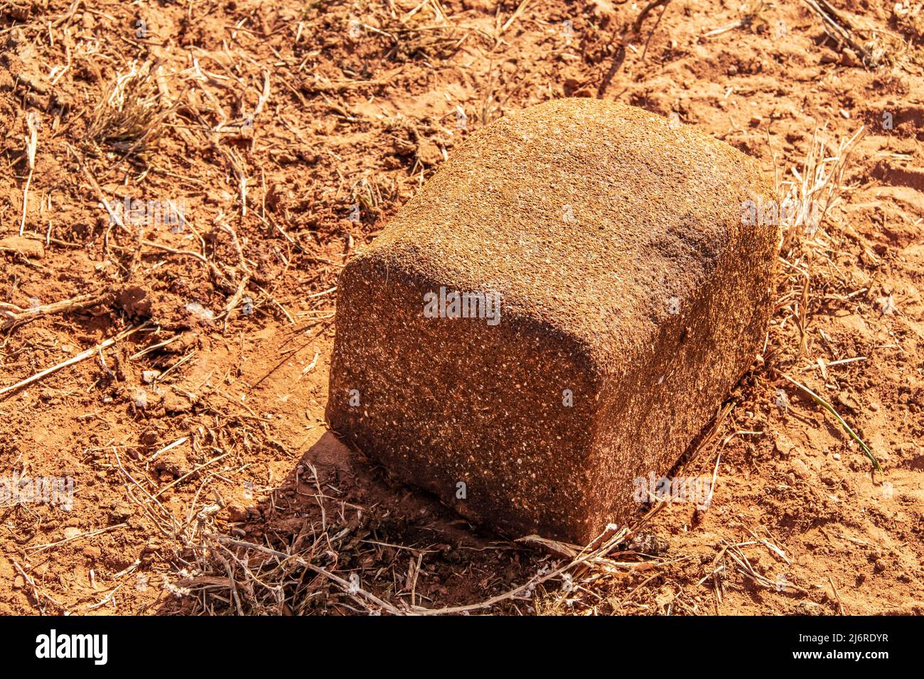 Nahaufnahme von Salz- oder Mineralblöcken für Rinder, die auf roter Erde liegen - teilweise auf roter, zerklumpter Erde geleckt, wo Tiere gestanden haben Stockfoto