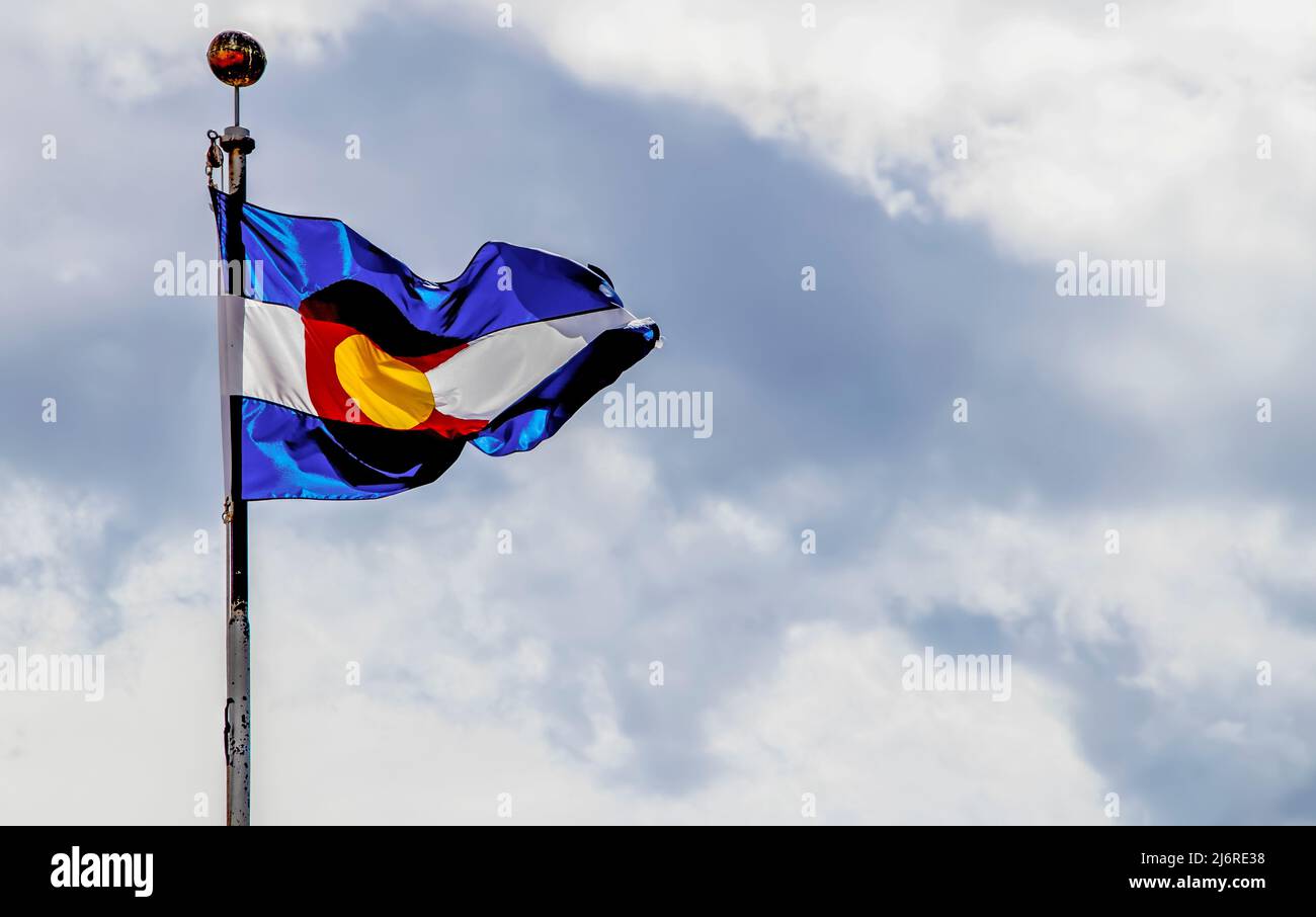 Colorado Flagge weht im Wind gegen stürmisch graublauen Himmel mit Wolken Stockfoto