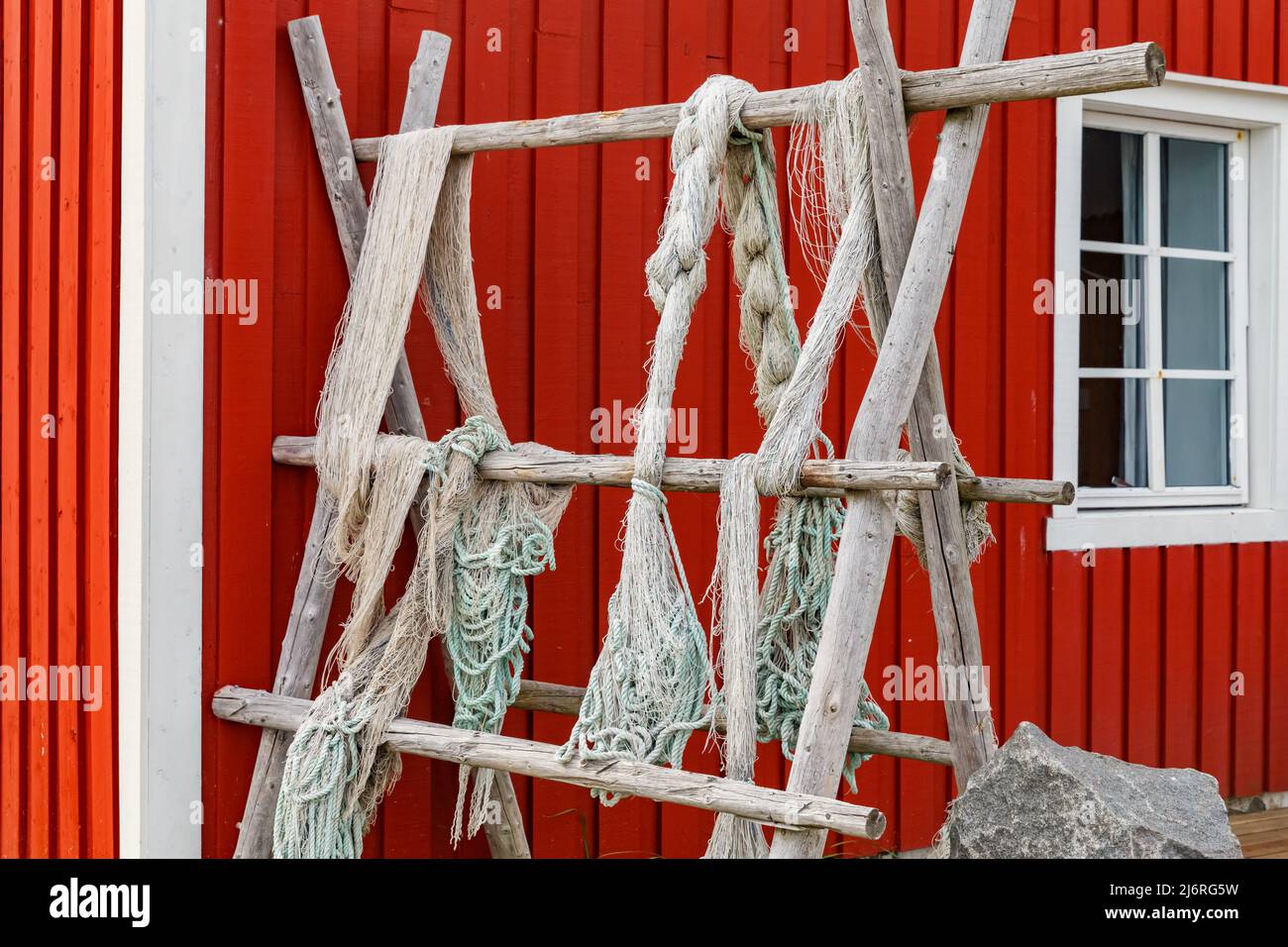 Lofoten-Inseln, Fischernetze, die am Zaun oder auf der Veranda hängen, klassische norwegische Landschaft, Haus von roter Farbe, Fischnetze sorgfältig ausgewählt Stockfoto
