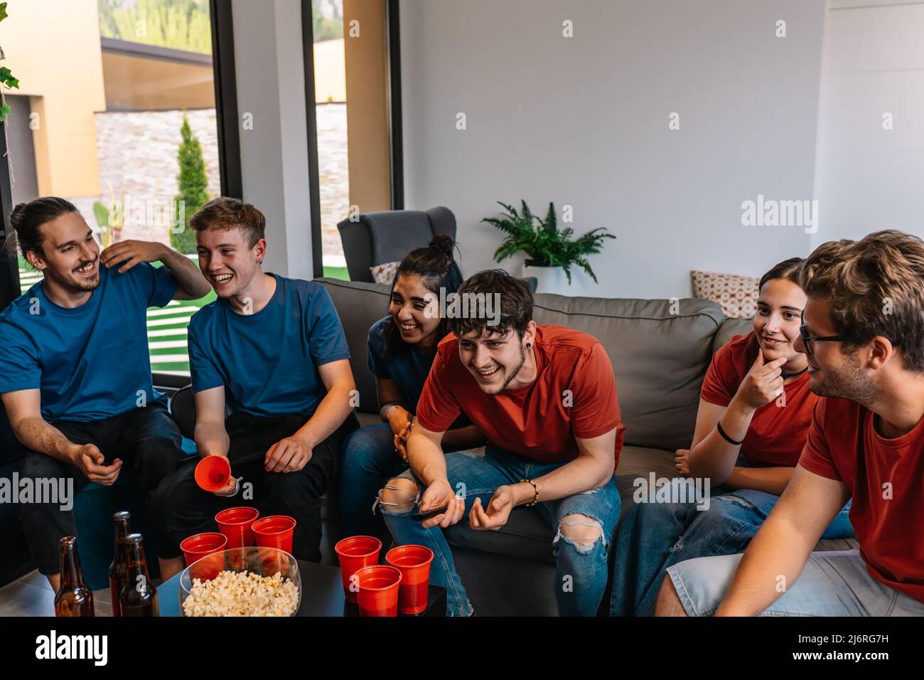 Freunde sehen sich ein Fußballspiel im Fernsehen an und kämpfen um ihr Team. Gruppe junger Menschen auf einer Party. Stockfoto