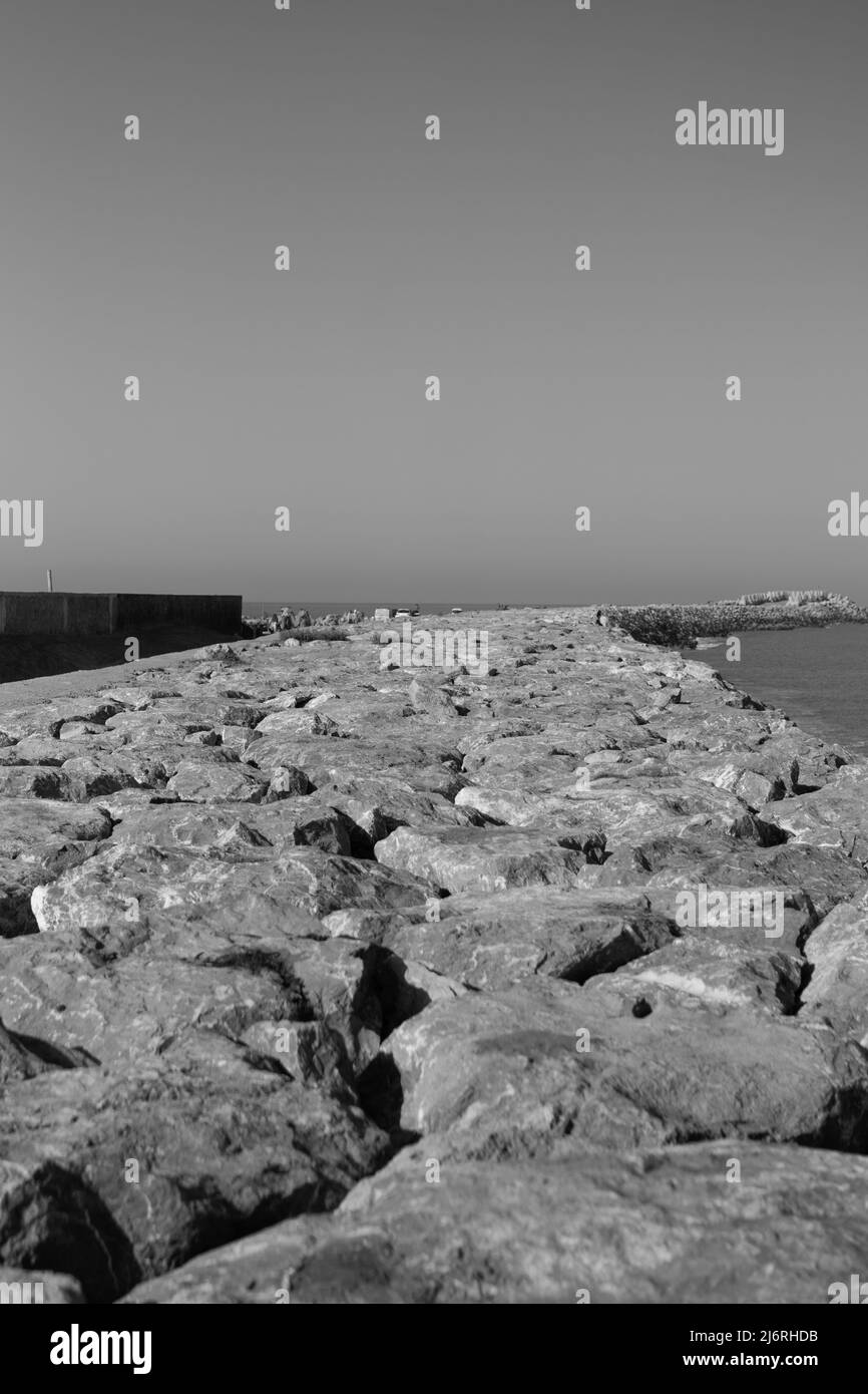 Das Meer rockt gegen den blau-klaren Himmel, Schwarz-Weiß-Fotografie Stockfoto