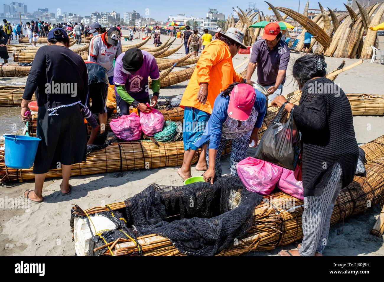 Einheimische Verkaufen Frischen Fisch Von Ihren Caballitos De Totora (Traditionelle Schilfboote), Pimentel Beach, Chiclayo, Provinz Chiclayo, Peru. Stockfoto