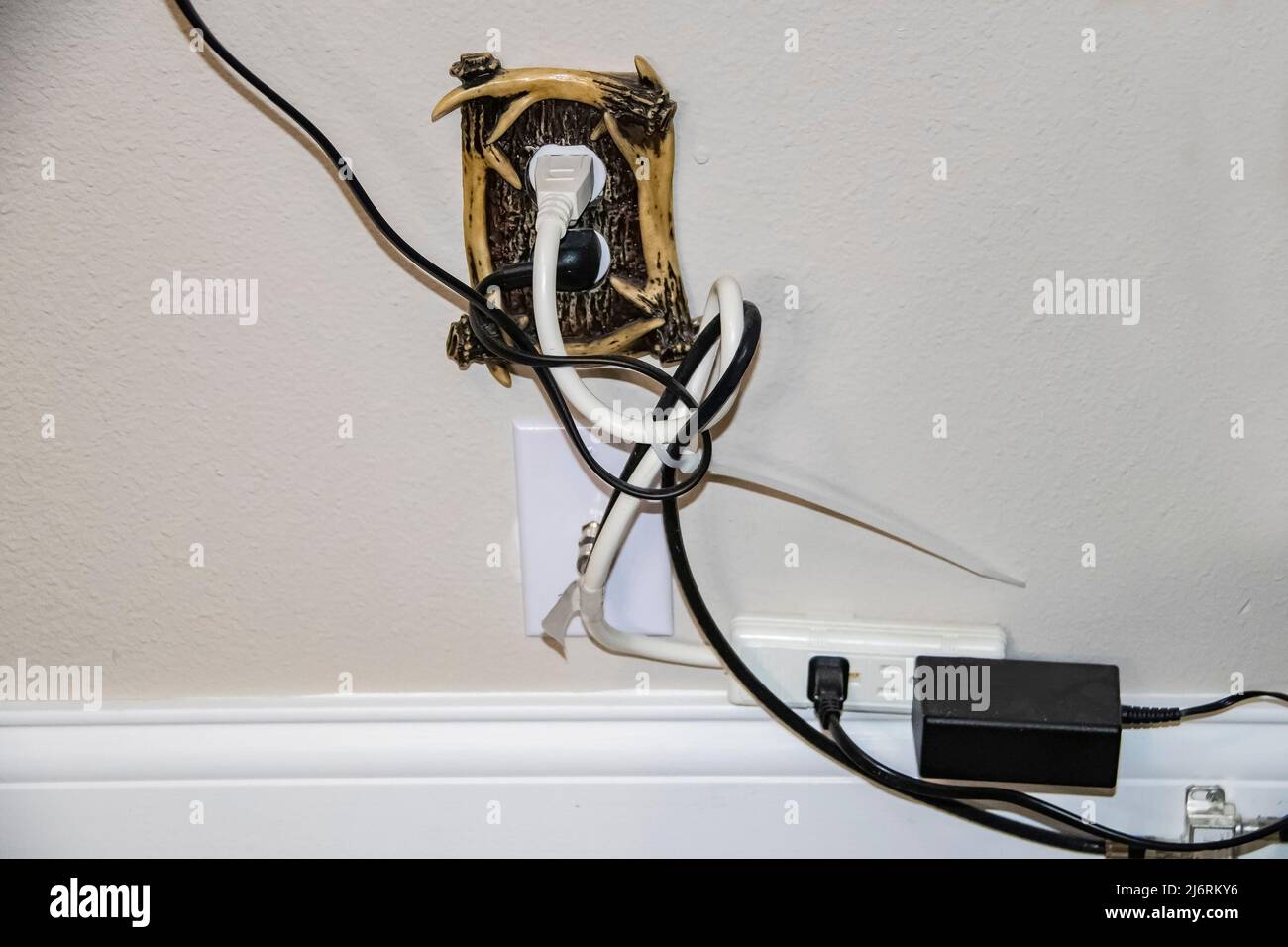Unordentliche Stromkabel - zu viele sind in eine dekorative Steckdose und ein Kabel gesteckt - alles in einem Gewirr Stockfoto