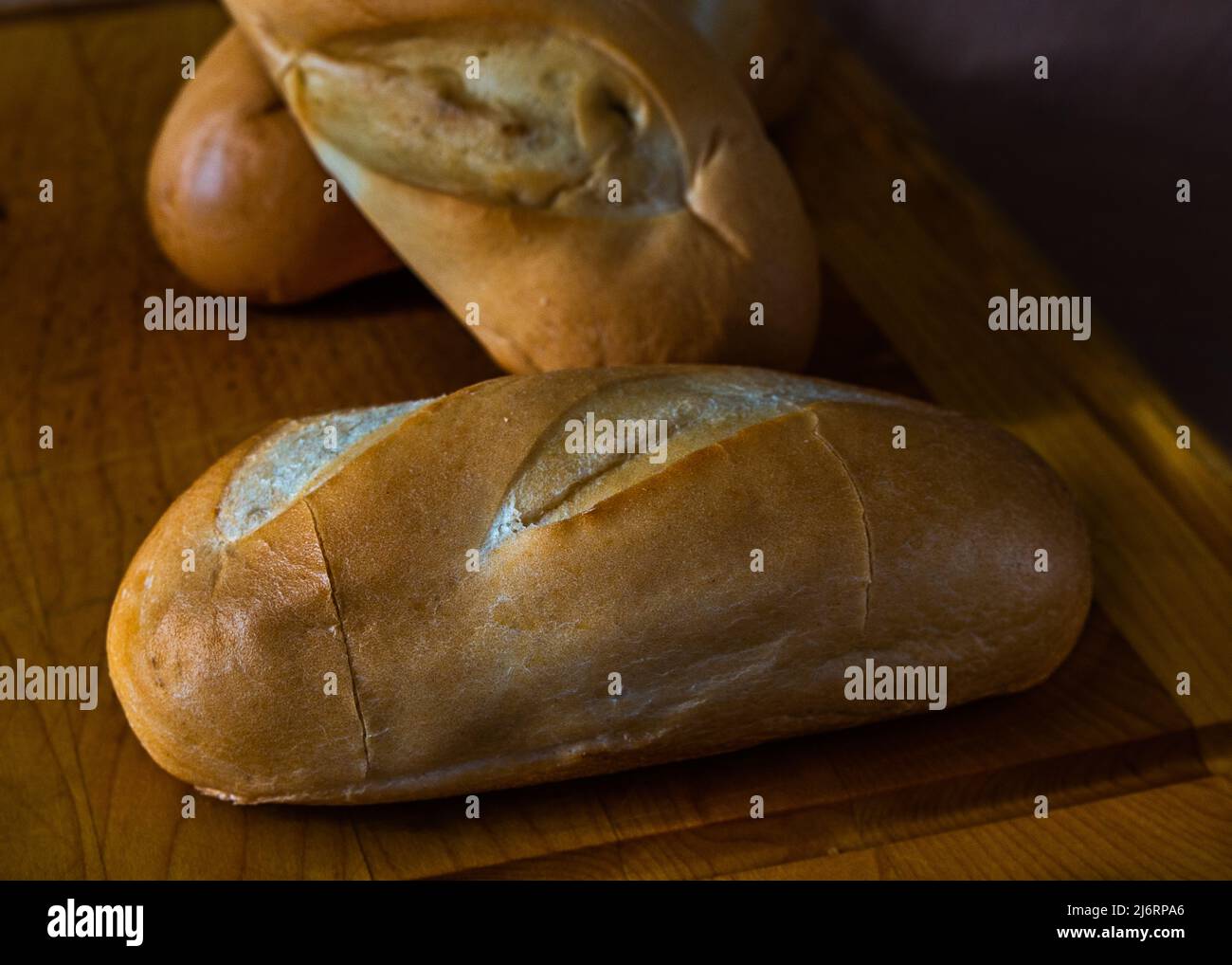 Frische hausgemachte Milchbrötchen, leckeres Brot, Brötchen, alles auf einem Schneidebrett und alles in Frühstücksatmosphäre. Stockfoto