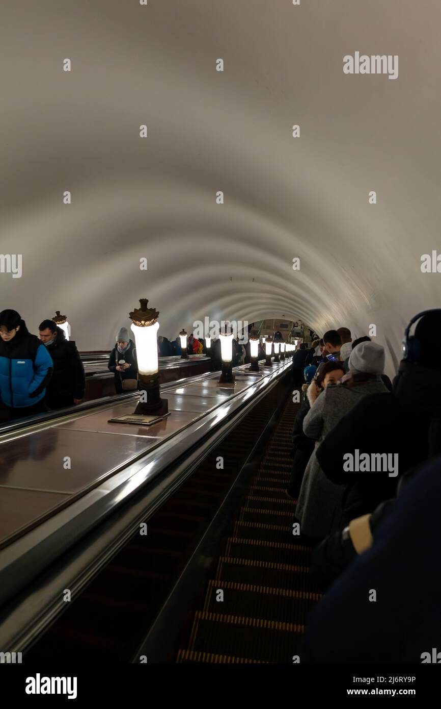 Die Leute gehen die Rolltreppe zur U-Bahn-Station hoch oder runter. Stadtleben, viele Menschen nutzen die öffentlichen Verkehrsmittel während der Hauptverkehrszeit. Stockfoto