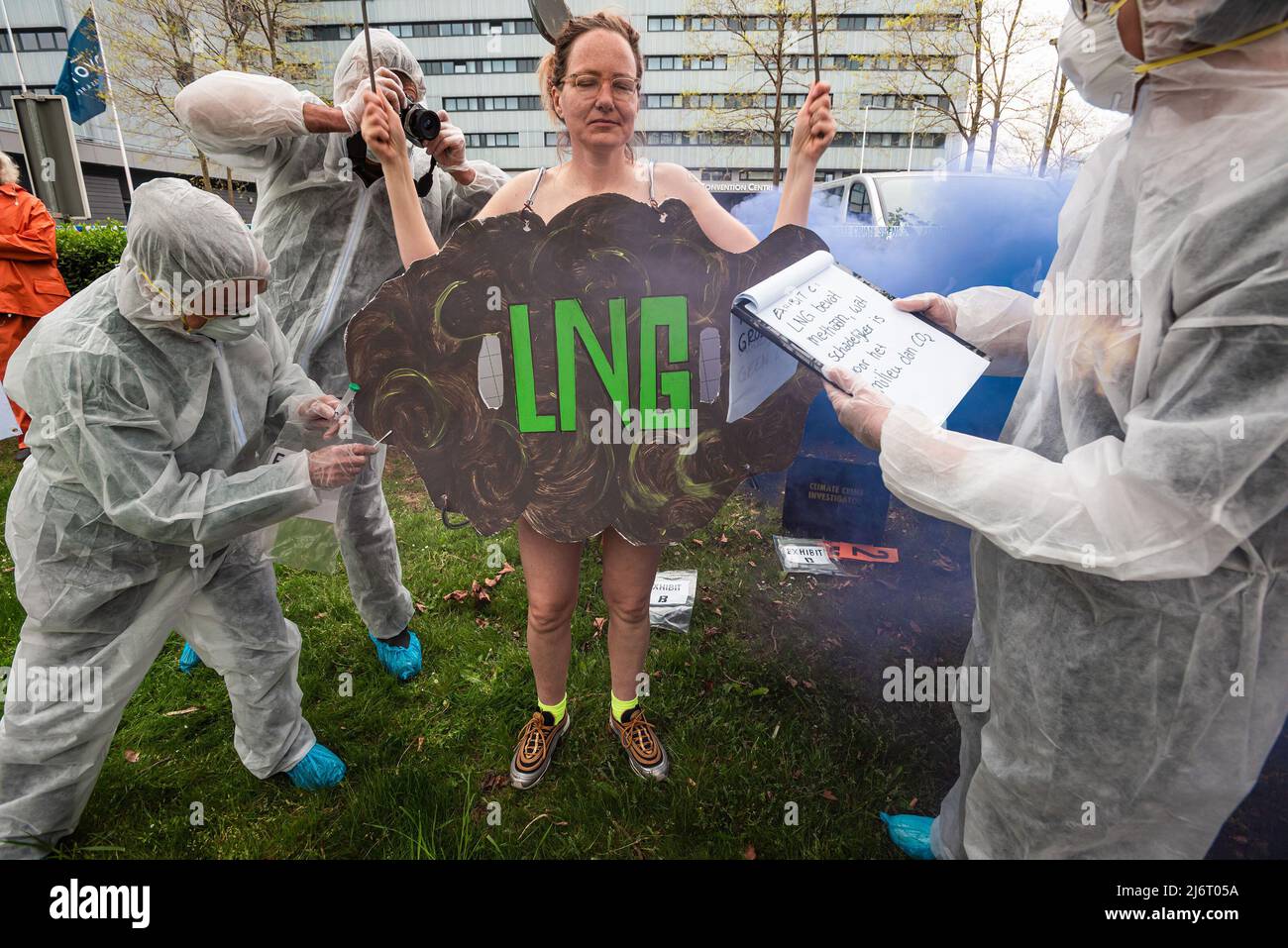 Die in blauem Rauch gestrahlte Demonstratorin der weiblichen Ozeanaufstand wird von den Ermittlern der Klimakriminalität während des Global LNG Bankering Summit beschuldigt, den Planeten verschmutzt zu haben. Während des Global LNG Bankering Summit 2022 stellt die Industrie fest, dass LNG oder Flüssigerd-Erdgas im Vergleich zu schwerem Heizöl der sauberste verfügbare Schiffskraftstoff ist. LNG hat deutlich geringere Emissionen von CO2 und fast nicht vorhandene Partikelemissionen und ist eine sichere Technologie, die einen höheren Energiegehalt und niedrigere Betriebskosten bietet. Ziel der 3-tägigen Konferenz ist es, den Start von Flüssig-Erdgas (LNG) in der Schifffahrt an zu initiieren Stockfoto